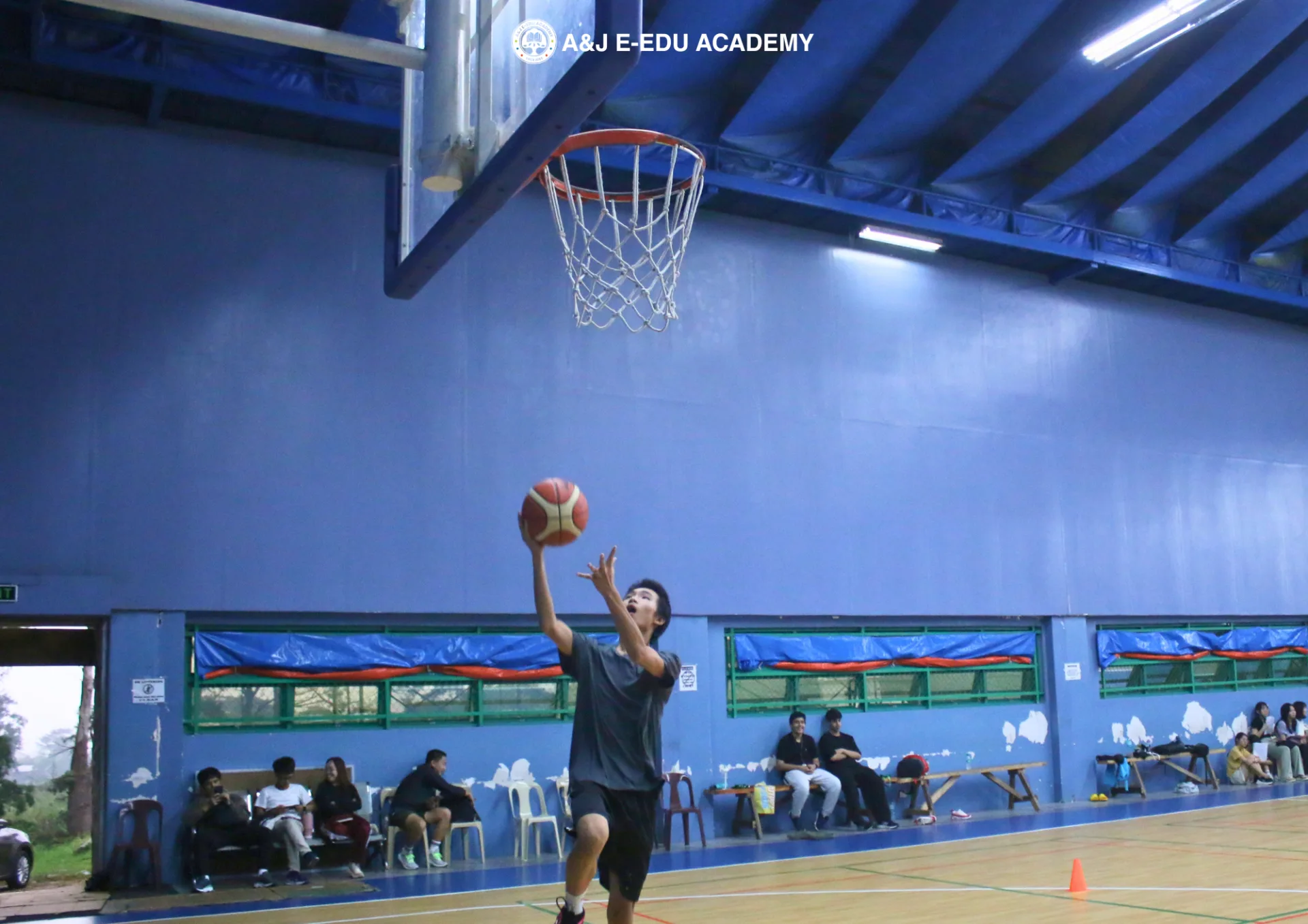 Junior student practices a layup during basketball class in the A&J indoor gym